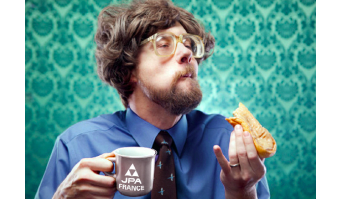 Photographie d'un homme mangeant une tartine avec dans l'autre main une tasse JPA France
