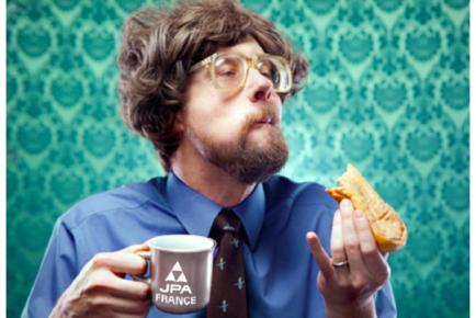Photographie d'un homme mangeant une tartine avec dans l'autre main une tasse JPA France