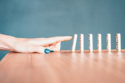 Photographie d'une main poussant des dominos